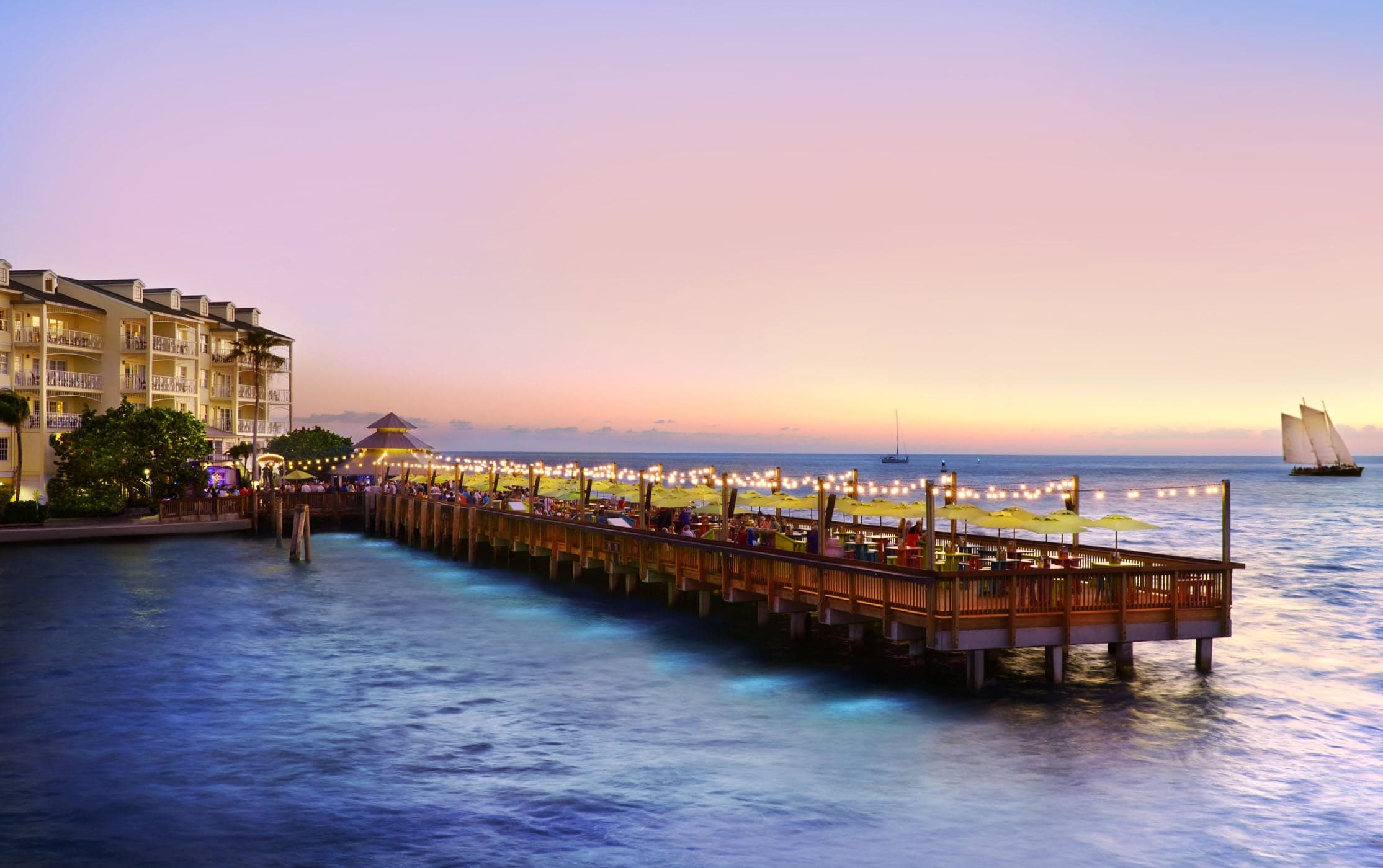The pier at sunset lit up with string lights at Ocean Key