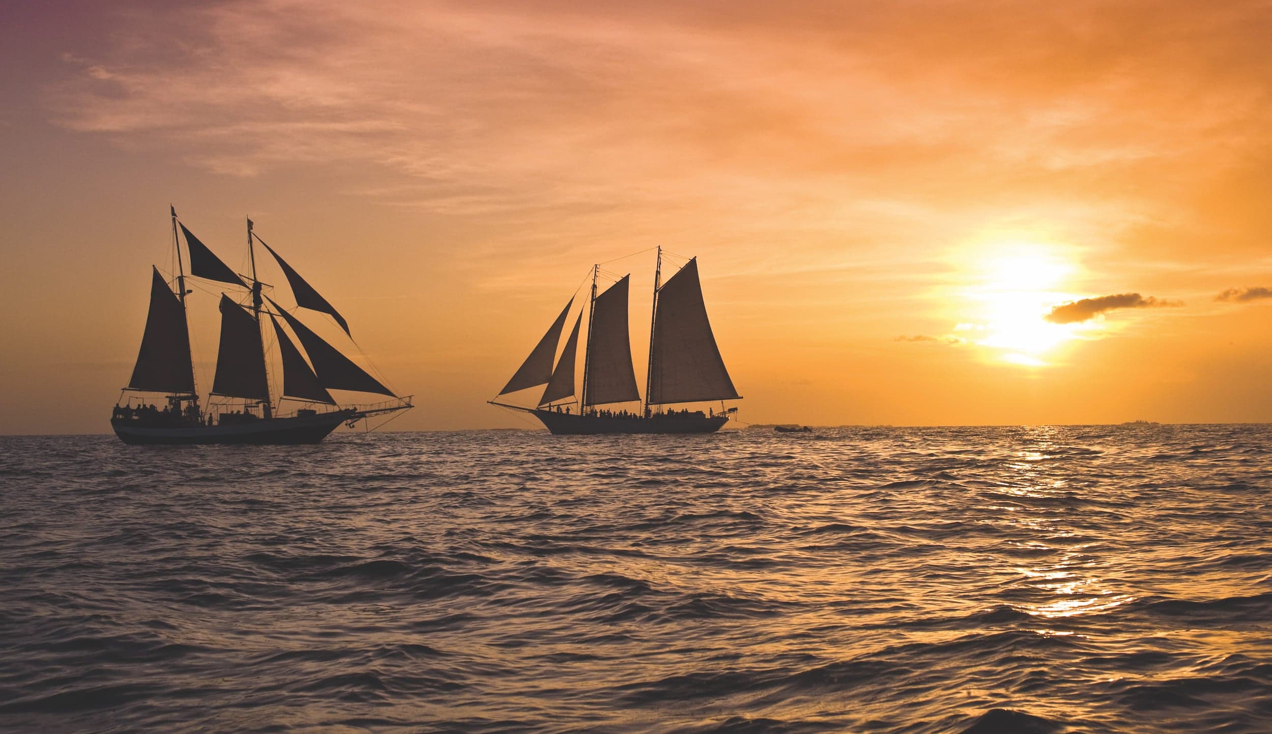 2 large sailboats on the water during a gorgeous sunset