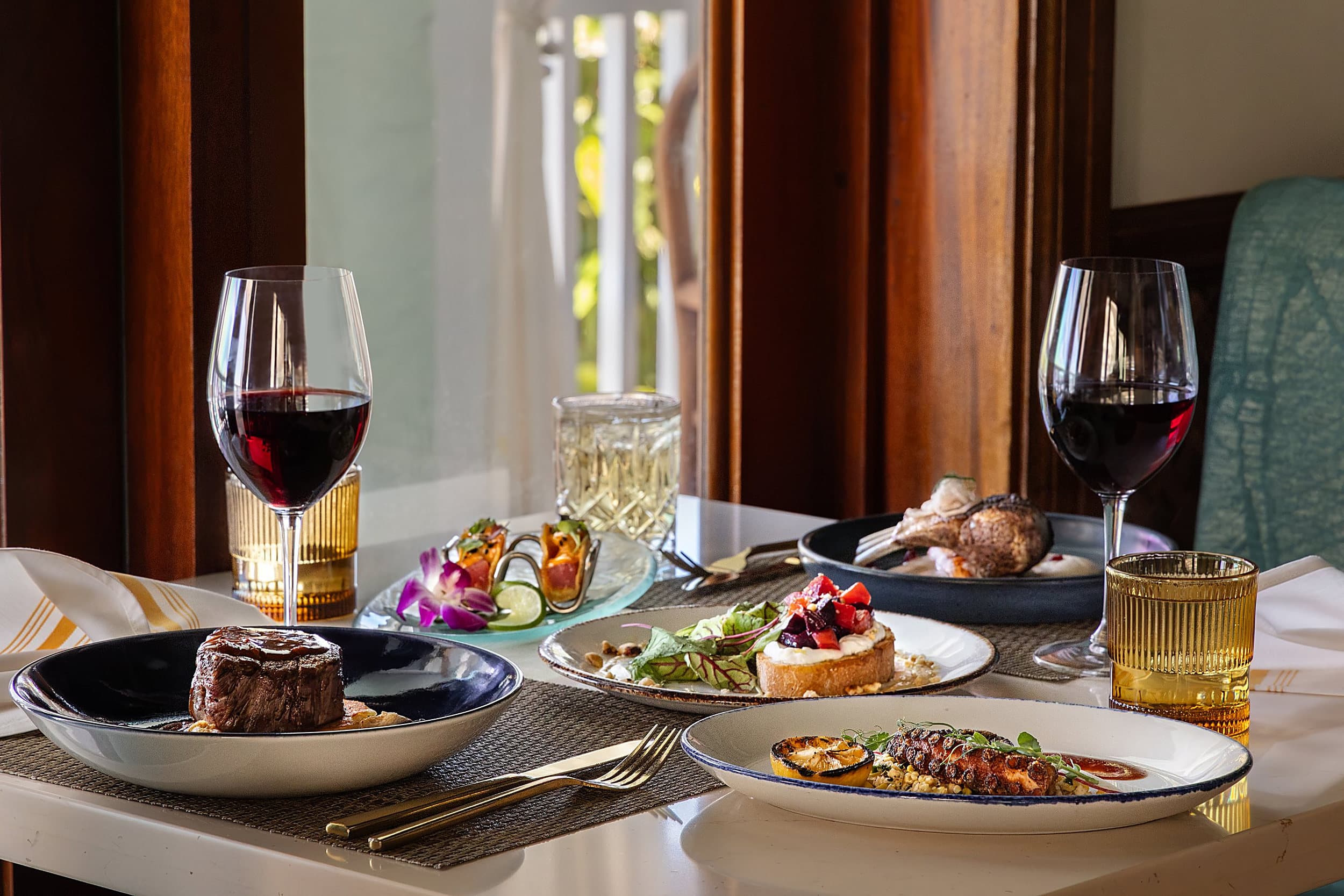 Filet mignon, grilled octopus, tuna tacos and red wine on a table at Hot Tin Roof, Ocean Key Resort in Key West, Florida